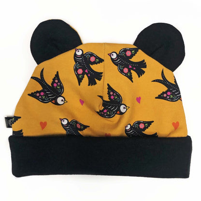 baby at with bear ears in a yellow and black muertos birds pattern 